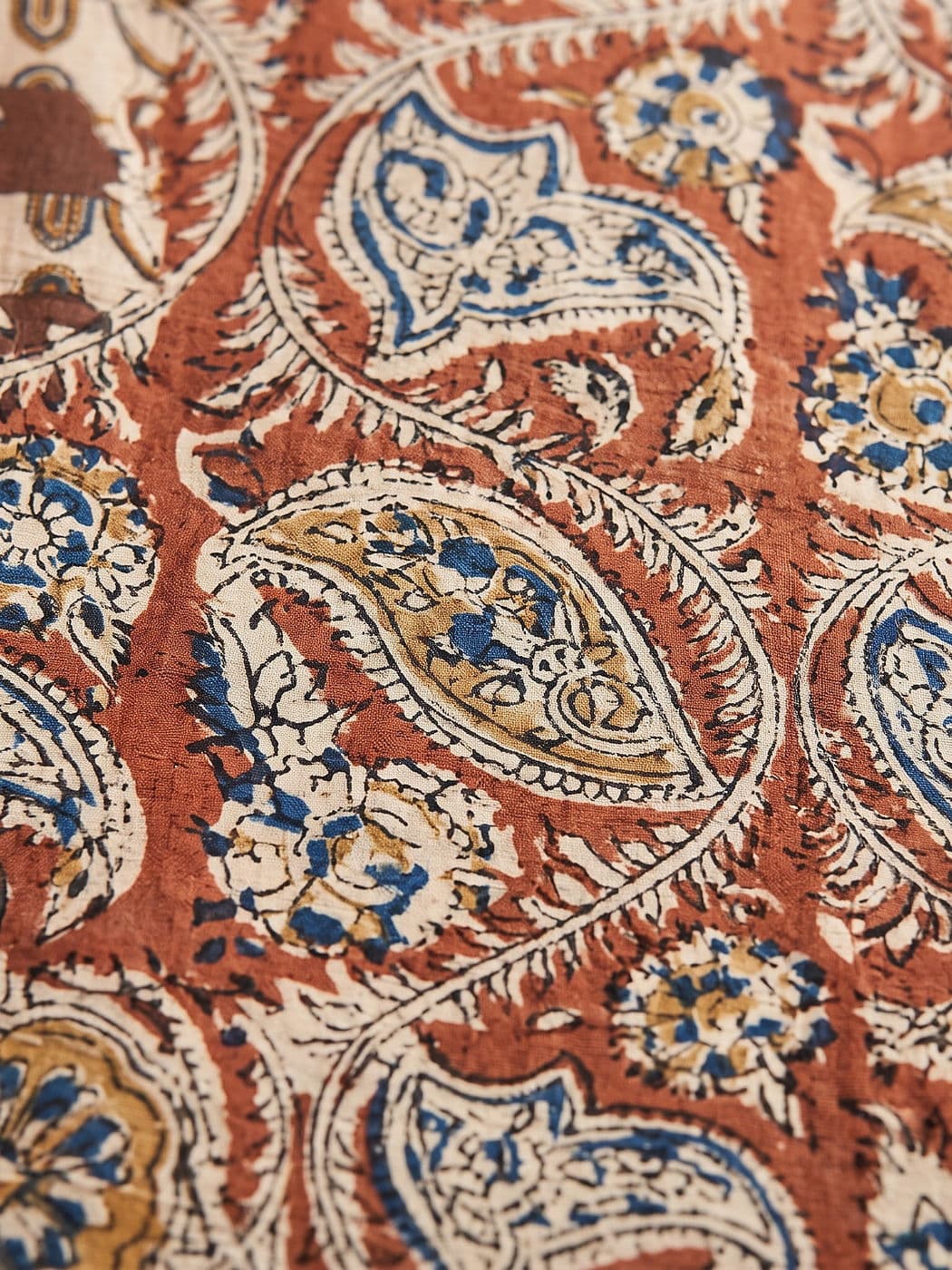 Close-up of the Ambika paisley: feathered cream outlines filled with indigo-blue and mustard flowers
