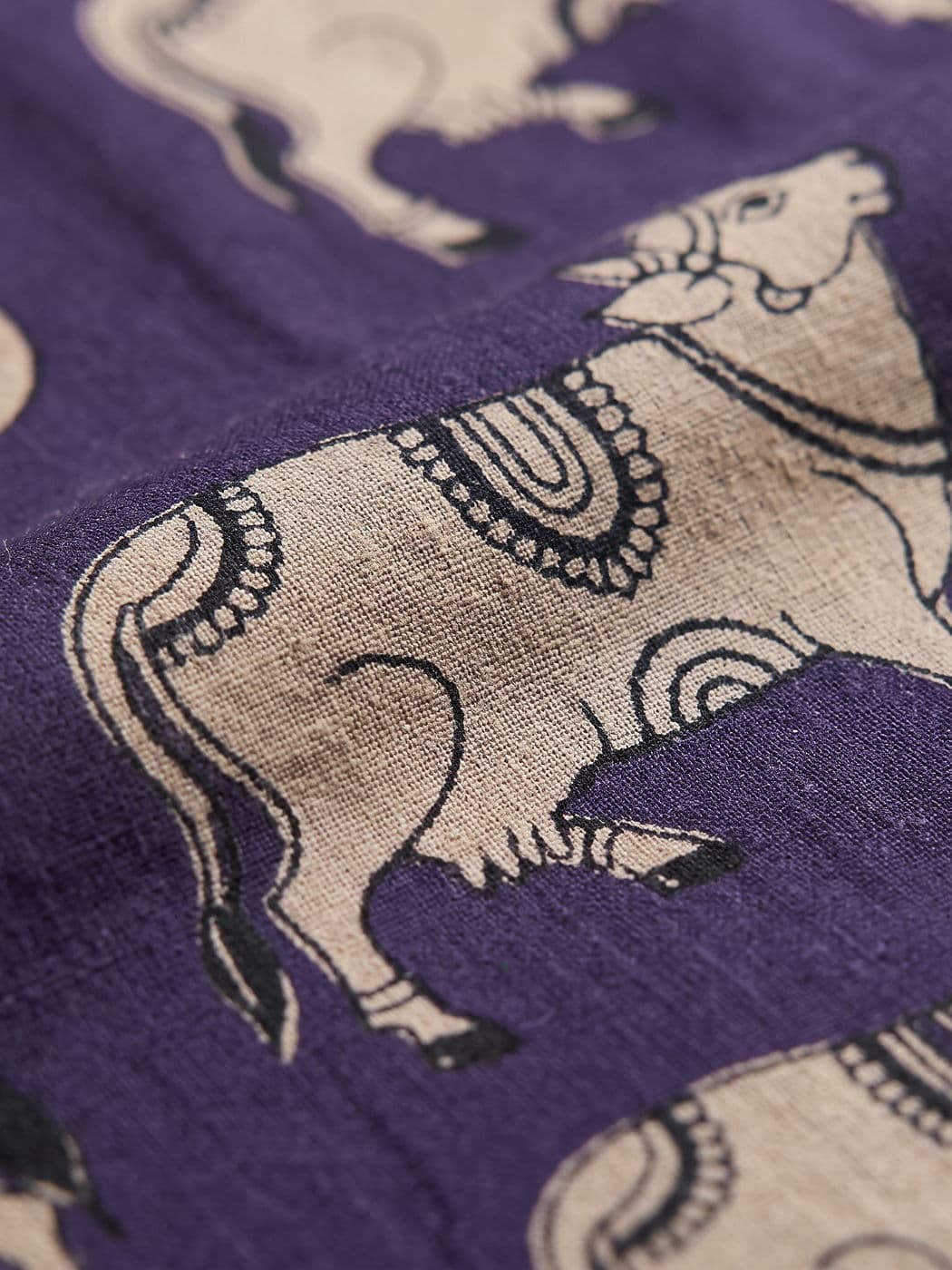 Close-up of one Nandi cow on the Gomati fabric, bells and garland drawn in a single black line