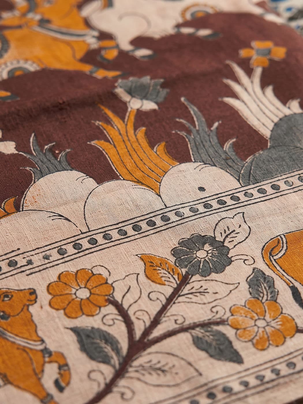 Close-up of the Nandini border: lotus buds, cream clouds, a dotted rule and a running vine with orange flowers
