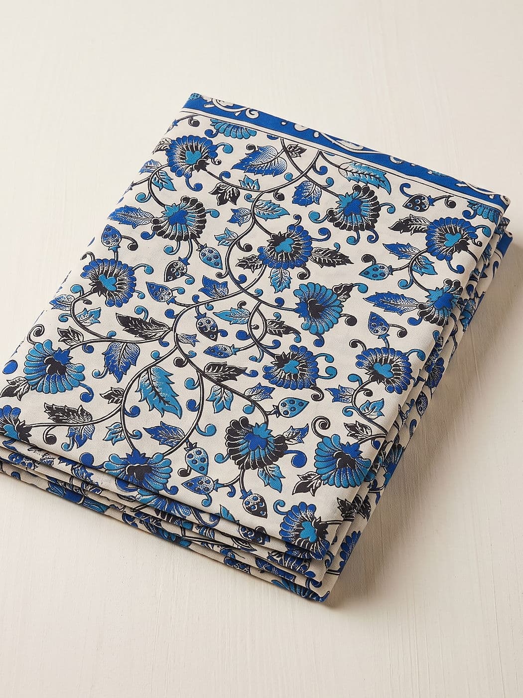 Neelambari blue floral Kalamkari cotton dupatta folded flat: blue flowers and black vines on cream, plain blue band along the selvedge